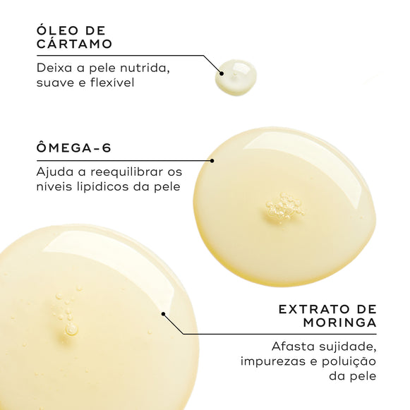 Close-up de gotas de óleo dourado num fundo branco. Linhas de texto destacam os ingredientes-chave: Óleo de Cártamo para deixar a pele nutrida, suave e flexível; Ómega-6 para ajudar a reequilibrar os níveis lipídicos da pele; e Extrato de Moringa para afastar sujidade, impurezas e poluição da pele.-hover-10