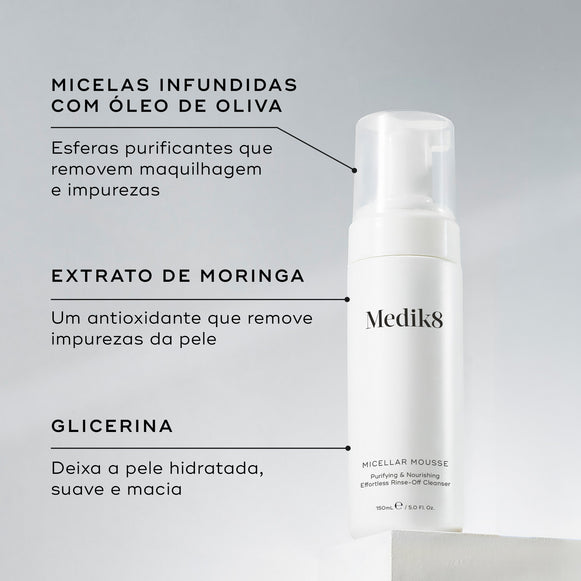 O frasco doseador Micellar Mousse assenta num pedestal branco contra um fundo cinza claro. Linhas de texto destacam os ingredientes-chave: Micelas Infundidas com Óleo de Oliva para remover maquilhagem e impurezas, Extrato de Moringa para remover impurezas da pele, e Glicerina para deixar a pele hidratada e macia.-hover-17