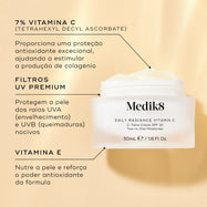 O frasco Daily Radiance Vitamin C está aberto num fundo bege. Linhas de texto destacam os ingredientes-chave: Vitamina C 7% (Ascorbato de Tetrahexildecil) para proteção antioxidante excecional e estimulação de colagénio, Filtros UV Premium para proteger contra os raios nocivos UVA e UVB, e Vitamina E para nutrir a pele e reforçar o poder antioxidante.