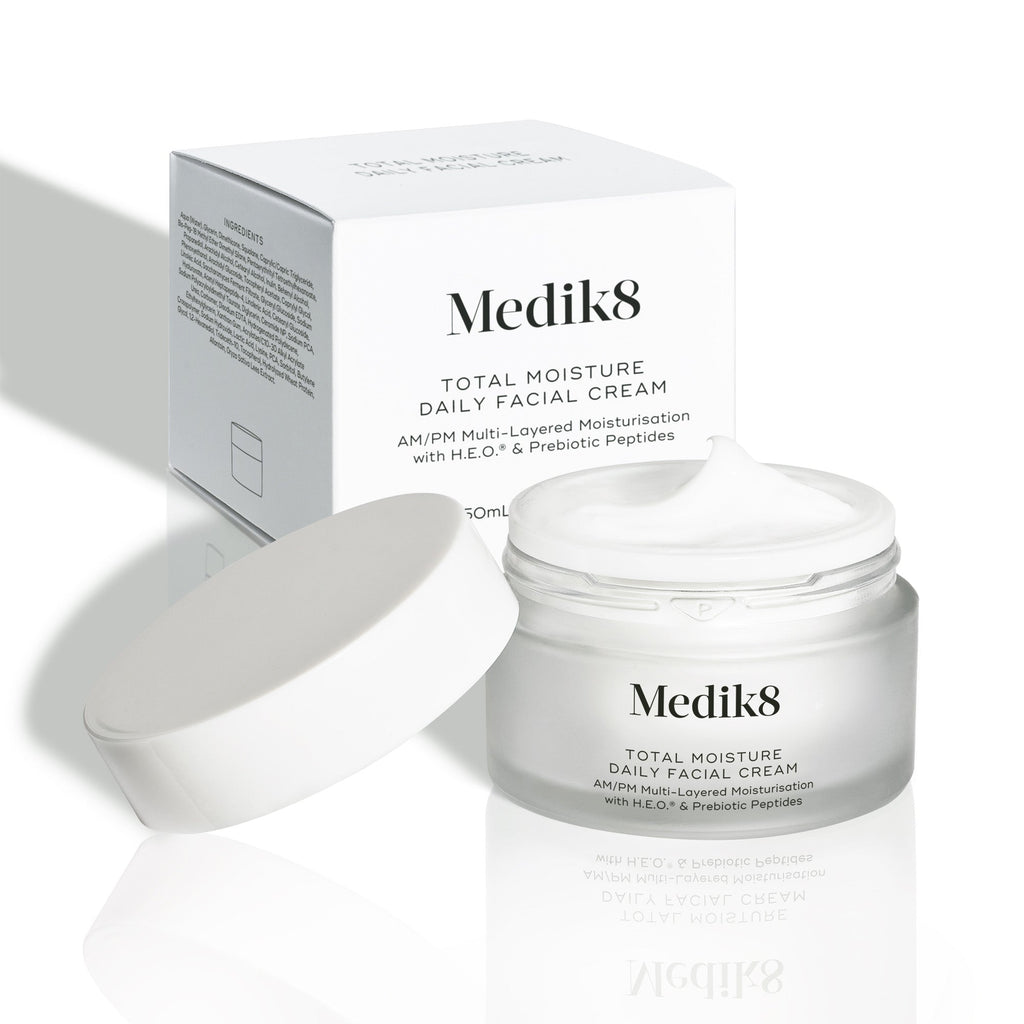 Um boião aberto de Total Moisture Daily Facial Cream juntamente com a sua embalagem de cartão branca.