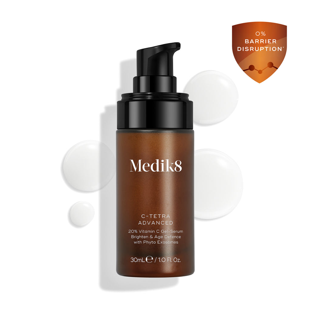 O frasco do sérum Medik8 C-Tetra Advanced é exibido sobre um fundo branco limpo com gotas de sérum translúcidas, destacando sua textura leve de sérum em gel. Um ícone de escudo laranja no canto destaca "0% INTERRUPÇÃO DA BARREIRA".
