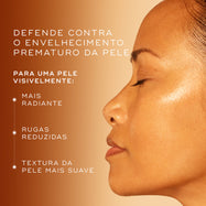 O perfil lateral do rosto de uma mulher com pele iluminada é mostrado sobre um fundo degradê laranja quente. O texto destaca que o produto defende contra o envelhecimento prematuro para uma pele visivelmente mais radiante, com rugas reduzidas e textura mais suave.