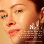 Um close-up de uma mulher tocando a sua bochecha luminosa contra um fundo bege quente. Um texto grande afirma que 87% dos utilizadores com pele sensível concorda que este é o sérum de vitamina C mais suave que já utilizaram.