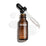 Uma imagem de produto vista de cima (“packshot”) de um frasco de 30 mL do sérum Medik8 C-Tetra  Vitamin C Serum. O frasco de vidro âmbar está sem tampa e colocado ao centro, com a tampa preta do conta-gotas apoiada na diagonal atrás do frasco. Um sérum líquido transparente está artisticamente espalhado e acumulado sobre o fundo branco limpo à volta do frasco, com algumas gotas visíveis na pipeta de vidro. A iluminação é intensa, criando sombras suaves à esquerda e uma estética clínica e elegan