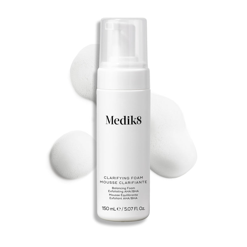 Frasco com doseador do Medik8 Clarifying Foam apresentado sobre um fundo branco limpo, com três porções de espuma branca e leve.