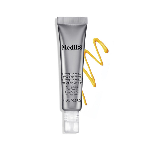Bisnaga do creme Medik8 Crystal Retinal Ceramide Eye 10 ao lado de uma amostra em ziguezague de creme amarelo, sobre um fundo branco.-hover-6
