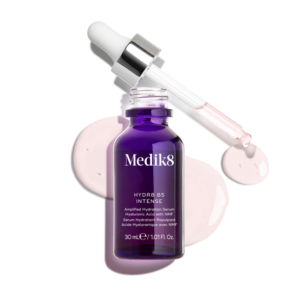 Frasco de vidro roxo escuro com conta-gotas do Medik8 Hydr8 B5 Intense, apresentado com a pipeta aberta posicionada sobre gotas de sérum rosa-claro, sobre um fundo branco limpo.-16