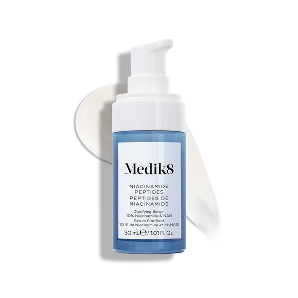 Frasco do sérum Medik8 Niacinamide Peptides com tampa de bomba branca, colocado sobre uma superfície branca com uma camada de sérum branco atrás, destacando a textura do produto.-14
