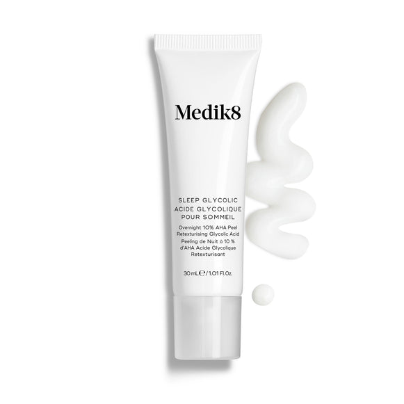 Bisnaga do Medik8 Sleep Glycolic apresentada sobre um fundo branco limpo, com uma camada ondulada e uma pequena gota de creme branco, destacando a sua textura.-33