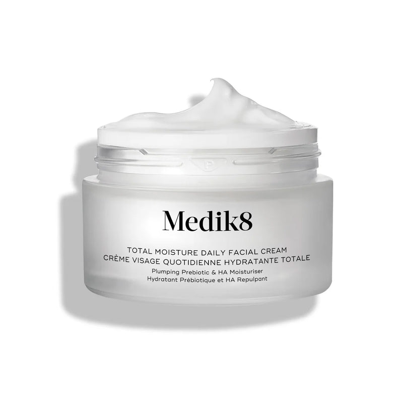 Frasco de vidro fosco aberto do creme Medik8 Total Moisture Daily Facial Cream, com uma porção de creme branco em relevo no topo, apresentado sobre um fundo branco limpo.