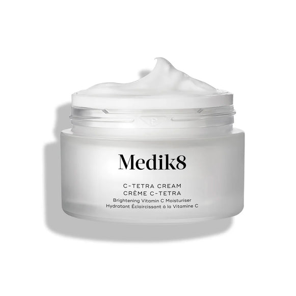 Frasco aberto do creme Medik8 C-Tetra Cream apresentado sobre um fundo branco limpo com sombras suaves. O frasco de vidro fosco branco apresenta o logótipo Medik8 e está identificado como “C-TETRA CREAM Vitamin C Cream” no formato de 50 mL. Uma espiral espessa de creme branco é visível no topo do frasco, destacando a sua textura hidratante.-27